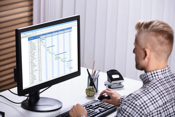 オフィスのデスクでコンピュータを使用してガントチャートを作成するビジネスマンのクローズアップ — ストック写真