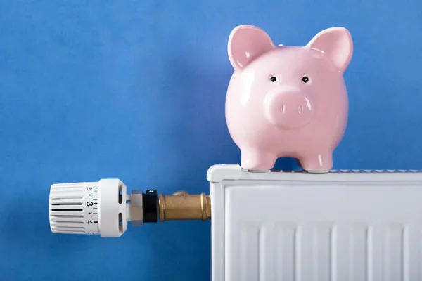 Close Van Piggy Bank Verwarming Radiator Tegen Blauwe Achtergrond — Stockfoto