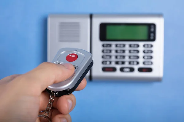 Primer Plano Mano Persona Usando Control Remoto Delante Alarma Seguridad —  Fotos de Stock