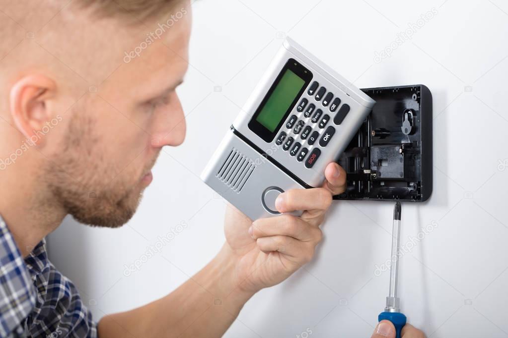 Young Male Technician Installing Security System Using Screwdriver