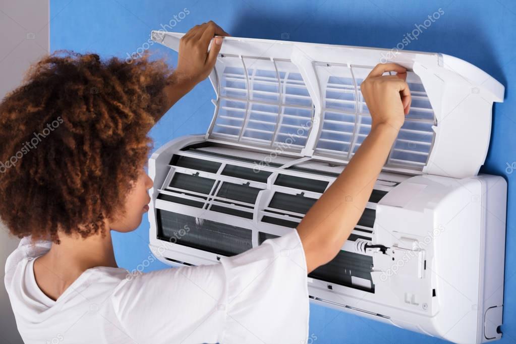 Close-up Of A Young Woman Checking Air Conditioner At Home