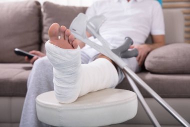 Kırık bacak uzak tutan koltukta oturan genç adam