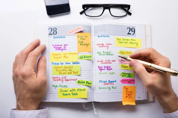 Kişinin el yazma Not Diary gözlük ve Mobilephone yüksek açılı görünüş