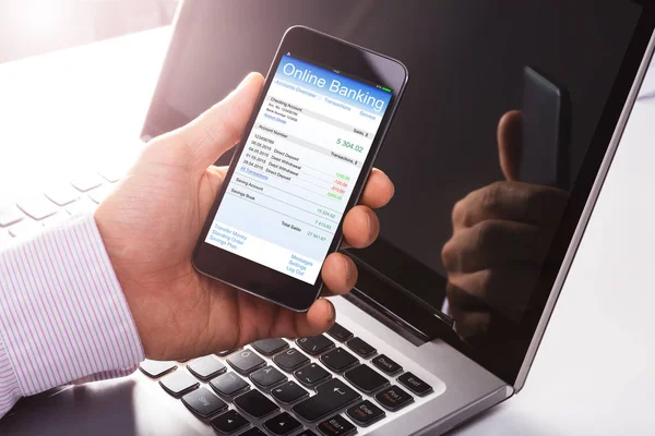 ノート パソコンの前で携帯電話でオンライン バンキングを使用して人間のクローズ アップ — ストック写真