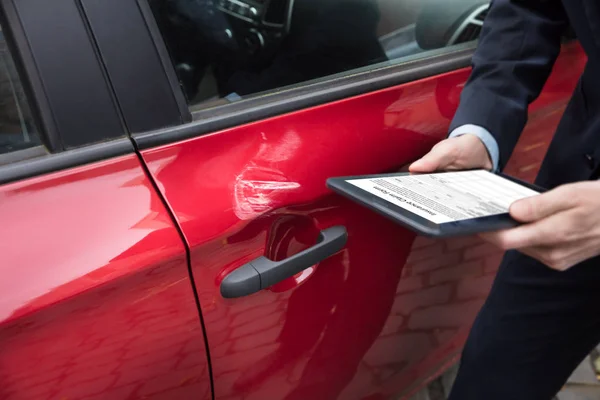 デジタル タブレットの画面で保険金請求フォームの表示と人の手の近くに赤い車 — ストック写真