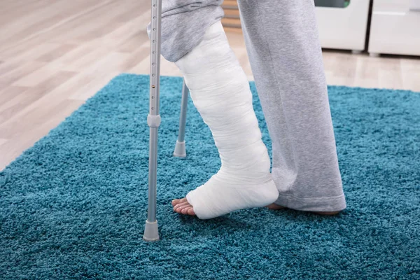 Kırık Bacak Mavi Halı Üzerinde Yürümek Için Koltuk Değneği Kullanarak — Stok fotoğraf