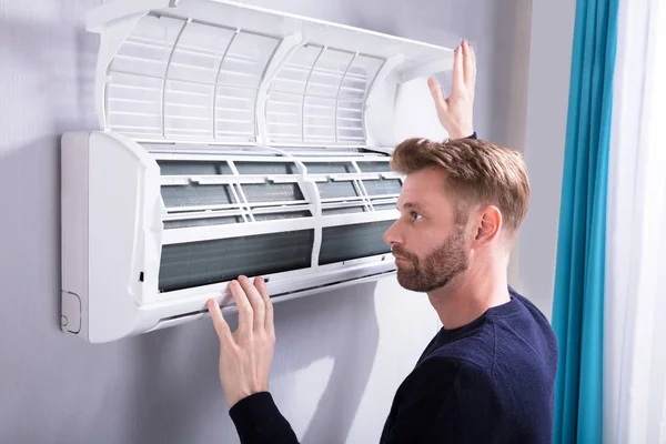 Close Van Een Jonge Man Controleren Airconditioner Gemonteerd Muur — Stockfoto