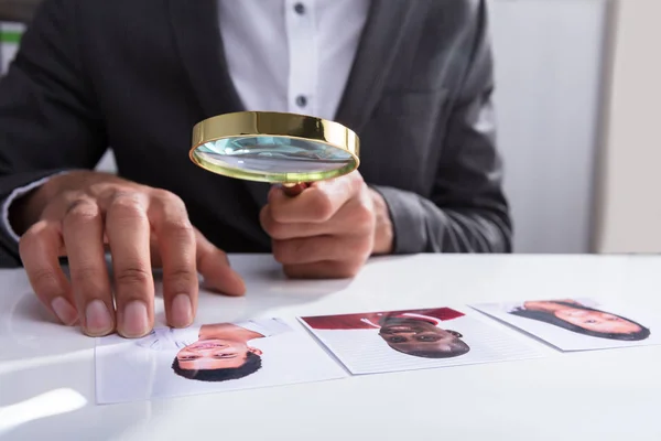 オフィスで虫眼鏡を通して申請者の写真を表示する実業家の手のクローズ アップ — ストック写真