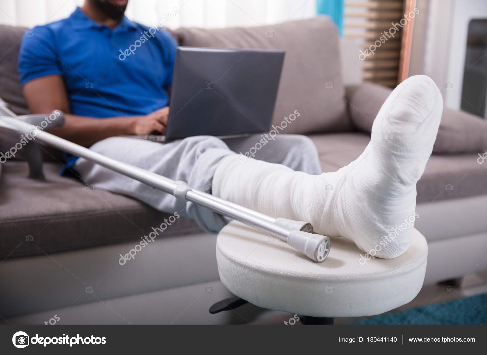 Man Broken Leg Sitting Sofa Using Laptop — Stock Photo © AndreyPopov 180441140