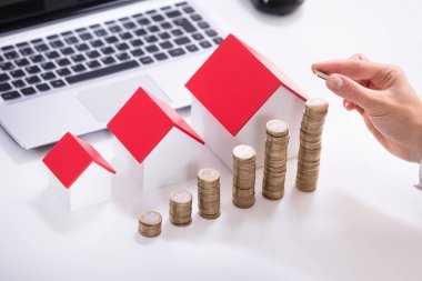 Yükseltilmiş bir işadamının'ın el paralar ile ev Model beyaz masa üzerinde istifleme görünümünü