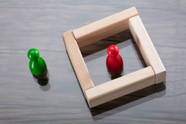 Yeşil heykelcik piyon yanı sıra ahşap bloklar çevrili kırmızı heykelcik piyon