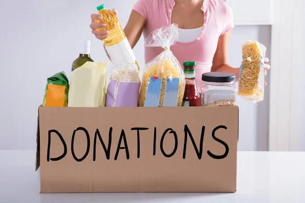 Midsection Kvinna Som Sätter Matvaror Donation Box Tabell — Stockfoto