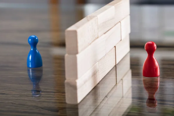 Close-up Of Red And Blue Figurine Paw Separated By Wooden Blocks On Desk