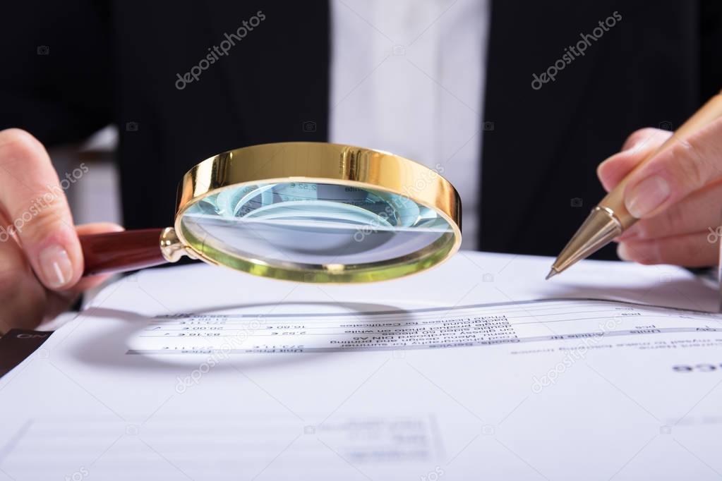 Close-up Of Auditor Inspecting Financial Documents At Desk