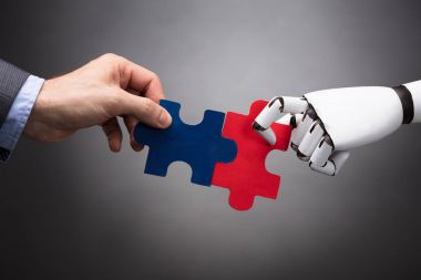 İşadamı ve Jigsaw tutan Robot gri arka plan üzerinde bulmaca