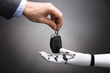 Robot gri arka plan üzerinde araba anahtarı veren bir işadamının'ın el Close-Up