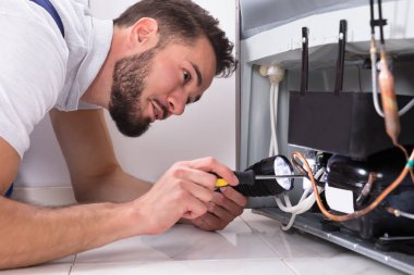 Erkek teknisyen tornavida ile buzdolabı tamiri fotoğrafı