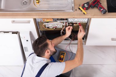 Erkek teknisyen bulaşık makinesi incelenmesi ile dijital multimetre
