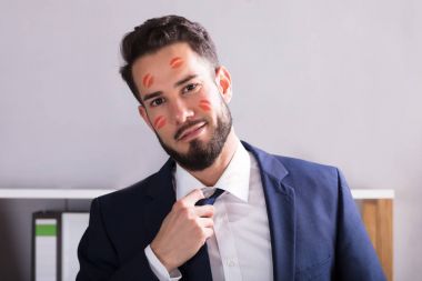 Close-up Of A Young Businessman With Lipstick Kiss Marks On Face clipart