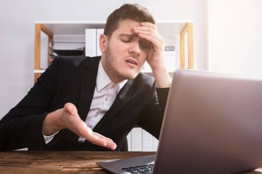 Office içinde Laptop bakarak üzgün genç işadamı