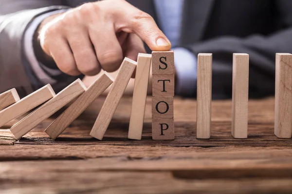 Geschäftsmann Stoppt Dominoeffekt Indem Den Finger Auf Hölzernen Anschlagblock Legt — Stockfoto