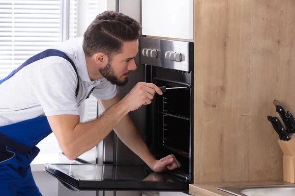 Genç Erkek Elektrikçi Mutfakta Tornavida Ile Fırın Tamiri — Stok fotoğraf