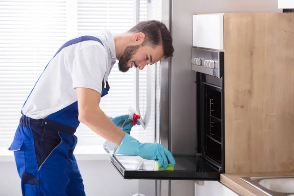 Ευτυχισμένος Αρσενικό Θυρωρών Που Καθαρίζουν Φούρνο Σφουγγάρι Στην Κουζίνα — Φωτογραφία Αρχείου