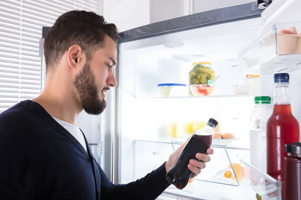 Close Açık Buzdolabı Içki Şişesi Tutan Genç Bir Adam — Stok fotoğraf