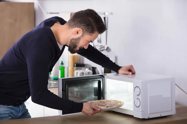 Vista Lateral Jovem Cozinhando Pizza Forno Microondas — Fotografia de Stock