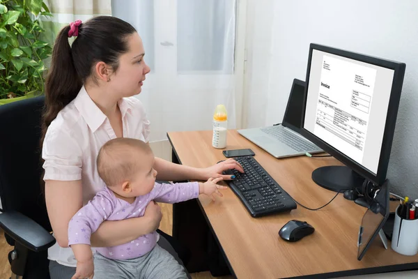 中年妇女与她的婴儿检查账单电脑 — 图库照片