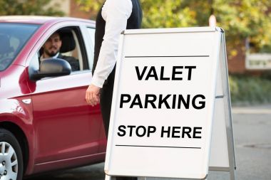 Gemide Valet Parking metnin önüne Vale yakınındaki arabada oturan işadamı duran