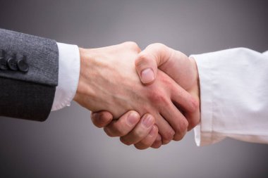 Doktor ve gri arka plan üzerinde tokalaşırken işadamı Close-Up