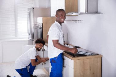 İki genç Handy erkeklerde Tekdüzen sabitleme İndüksiyon Ocağı ve boru mutfak lavabo