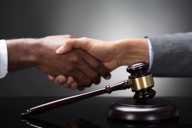 Çekiç ve gri arka plan karşı el sıkışan iki iş adamları önünde tokmak