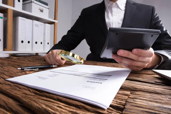 Mano Del Empresario Analizando Factura Con Lupa Escritorio Madera — Foto de Stock