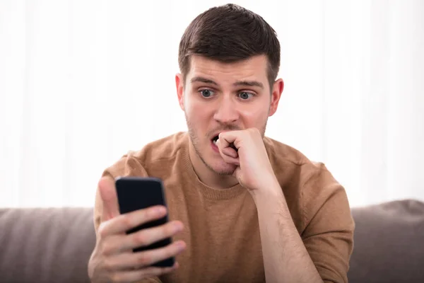 Jonge Man Kijkend Naar Smartphone Bezorgd Sofa Thuis Zit — Stockfoto