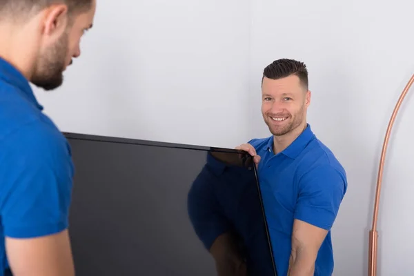 Dos Jóvenes Hombres Mudan Uniforme Colocando Televisión Sala Estar —  Fotos de Stock