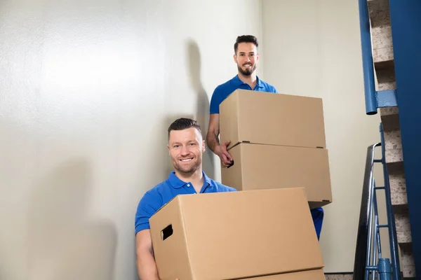 Dvě Mladé Mužské Movers Modrém Jednotné Provedení Lepenkových Krabicích Schodiště — Stock fotografie