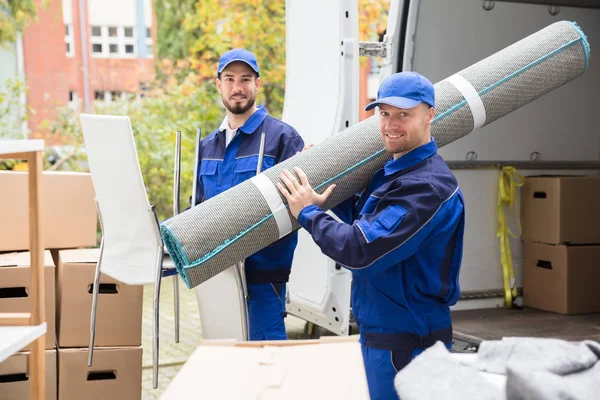 Två Leende Leverans Män Innehar Stolar Och Matta Framför Lastbil — Stockfoto