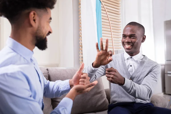 Two Young Happy Men Sitting Sofa Making Sign Languages — Stock Photo, Image