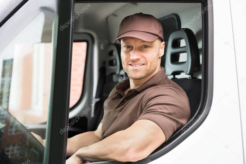 Portrait Of A Happy Young Delivery Man Sitting Inside Van