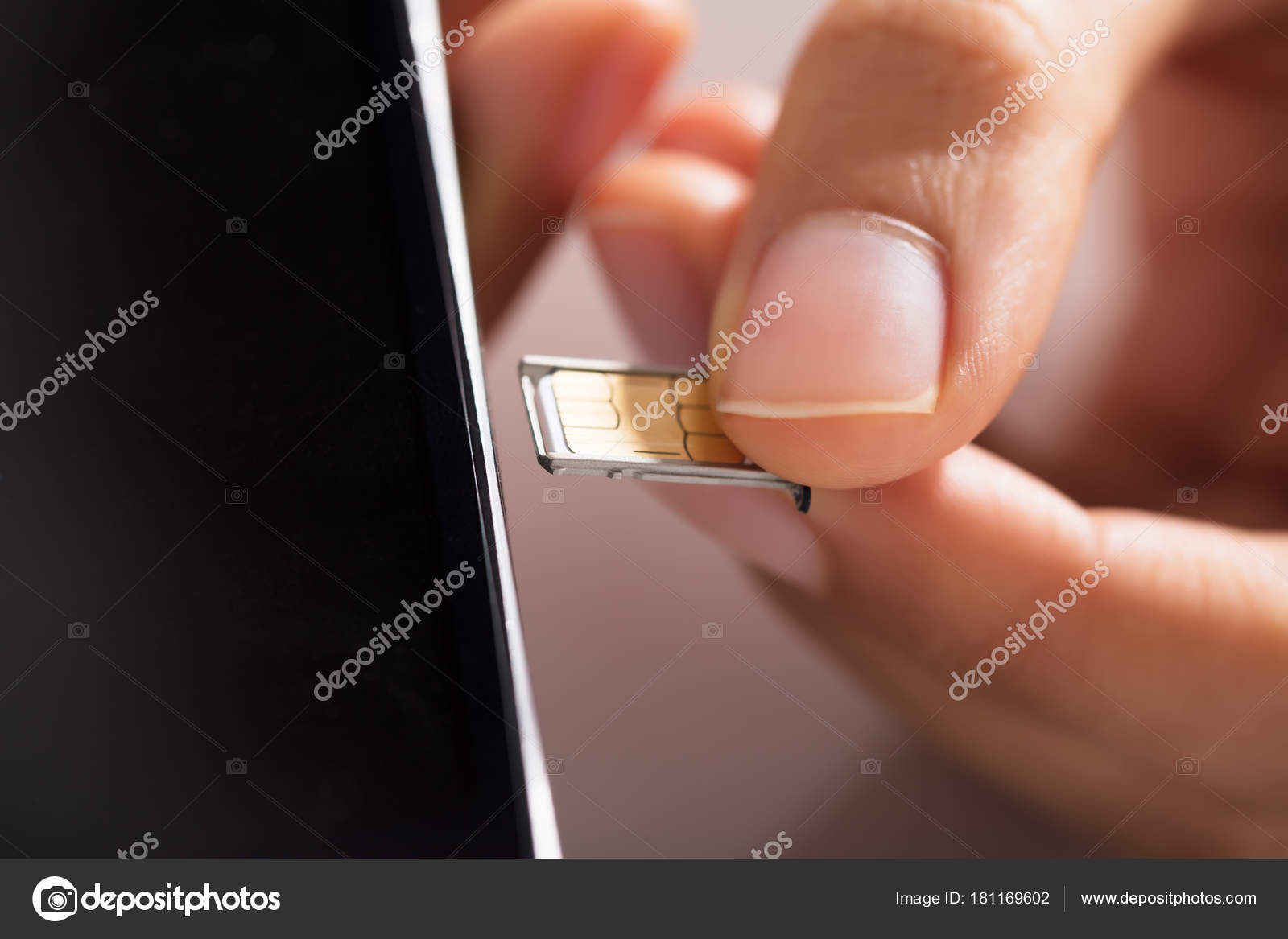  A person carefully inserts a SIM card into the side of a mobile phone.