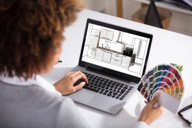 Renk seçimi için dizüstü bilgisayar ekranında mutfak çizim üzerinde çalışan bir kadın mimar