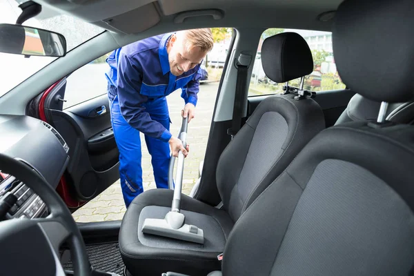 掃除機を車の座席の掃除機をかける若い幸福な労働者 — ストック写真