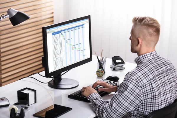 オフィスのデスクでコンピュータを使用してガントチャートを作成するビジネスマンのクローズアップ — ストック写真