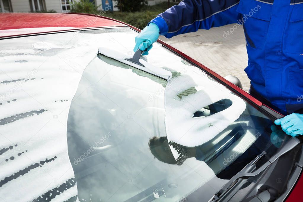 Worker Washing Windshield Of A Car With Squeegee