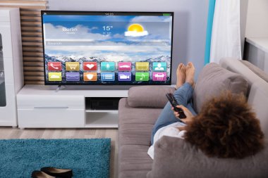 Ekranda renkli uygulamaları ile televizyon izlerken kanepede yatan kadın