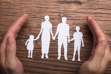 Ahşap üzerine aile Papercut koruyan kişi el yüksek açılı görünüş