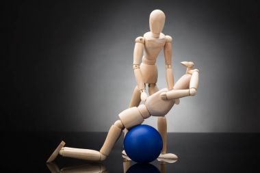 Ahşap heykelcik mavi Fitness topu gri arka plan üzerinde egzersiz yaparken yardımcı antrenör
