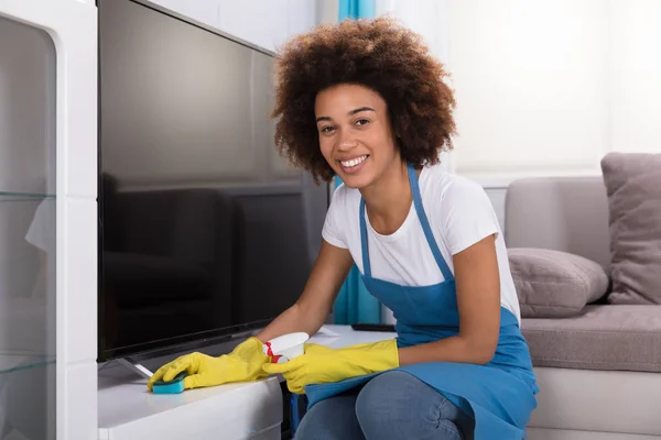 年轻女清洁工家用海绵清洁家具 — 图库照片